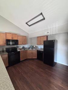 a kitchen with a black refrigerator and wooden cabinets at Modern & Cozy Apartment Stay in Olathe