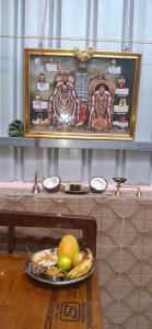 ティルヴァンナーマライにあるSivagini rooms - 5 minutes walk from arunachaleshwara templeの絵が飾られたテーブルの上に置かれた果物の皿