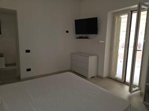 1 dormitorio blanco con 1 cama y TV en la pared en The Dreams Palace, en Porto San Paolo