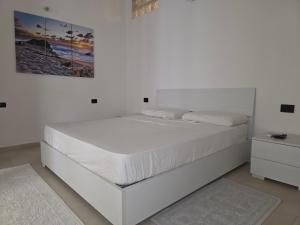 Dormitorio blanco con cama blanca y mesita de noche en The Dreams Palace, en Porto San Paolo