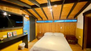 a bedroom with a bed and a flat screen tv at Casa Mosaiko Sonsón in Sonsón