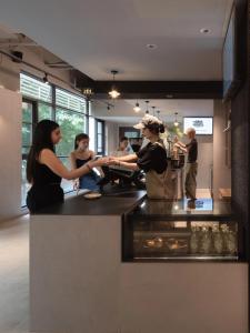 a group of people standing around a counter in a kitchen at Guangzhou Desti Youth Hostel - Rainbow Bridge Metro Station in Guangzhou
