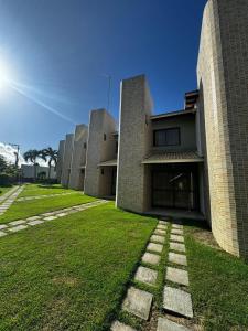 a building with a grassy yard in front of it at Village duplex Guarajuba 3 suítes in Camacari