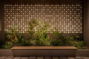 a bench in front of a wall with plants at THE NEST NAHA in Naha