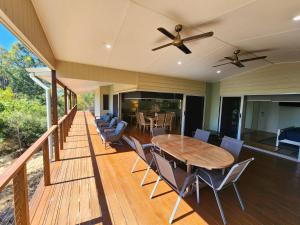 a wooden deck with a wooden table and chairs at Avoca Holiday House Fraser Island in Kingfisher Bay