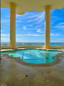 ein Swimmingpool mit Säulen und dem Meer im Hintergrund in der Unterkunft Cabrero Beach 906 in Cartagena de Indias