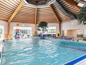 a large swimming pool in a large building with a large ceiling at Holiday Home by the Sea in Brouwershaven