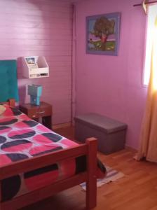 a bedroom with a purple wall with a bed and a ottoman at La laguna Parral in Parral +5 photos