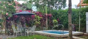 a table with chairs and an umbrella next to a pool at Arenals Peak Villas in Agua Azul