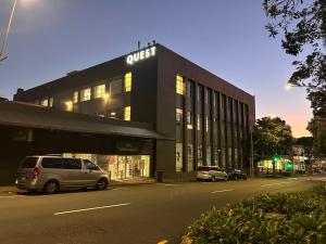 a building with cars parked in front of a street at Quest New Plymouth CBD Apartment Hotel in New Plymouth