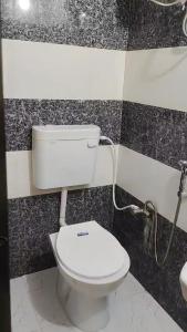 y baño con aseo en una pared de azulejos blanco y negro. en Ramansh Home stay, en Ayodhya 11 fotos más