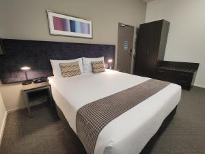a bedroom with a large white bed and a desk at Quest New Plymouth CBD Apartment Hotel in New Plymouth
