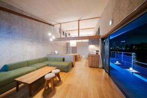 a living room with a green couch and a bed at TUGBOAT Suite in Osaka