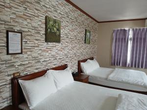 a bedroom with two beds and a stone wall at Ju Jia Xiao Zhan Homestay in Guanshan