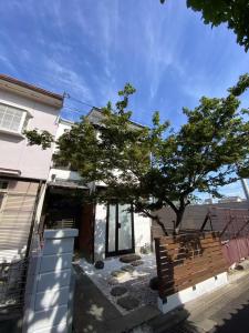 a tree in front of a house with a bench at 夏様四条大宮 四条大宮駅5分 京都市中心部 一棟一組貸切 広い庭付き一戸建て in Kyoto