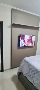 a bedroom with a flat screen tv on the wall at Apto familiar a 6 kms do aeroporto in Brasilia