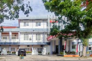 a white building with a tree in front of it at RedDoorz Syariah at Edotel Bundo Kanduang Padang in Kampungdurian