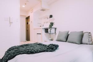 Una cama blanca con una manta negra encima en Minimalist Loft 3 Namba Compact Studio and 24 hours Gym 01, en Osaka