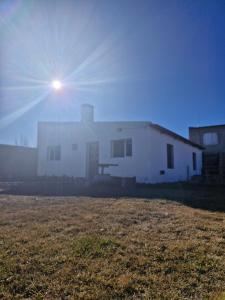 a large white house with the sun in the sky at Hospedaje Patagonia Sur in Gobernador Gregores