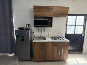 a small kitchen with a refrigerator and a sink at Loft Cinema Alfredo Mochileando in Tamiahua