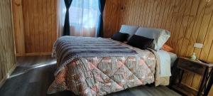 a bedroom with a bed with a blanket and a window at Cabañas Pinos del Mar in Algarrobo