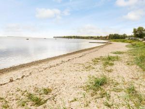 a sandy beach next to a body of water at 6 person holiday home in Sjølund-By Traum in Binderup Strand