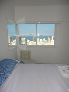 Habitación blanca con cama y ventana en Ipanema's heart, en Río de Janeiro