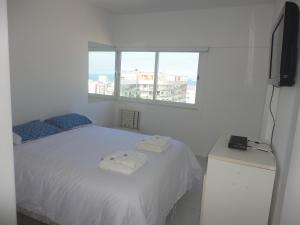 1 dormitorio con cama blanca y ventana en Ipanema's heart, en Río de Janeiro