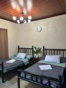 two beds in a room with a clock on the wall at Kabbalay Homestay in San Juan