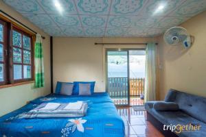 a bedroom with a blue bed and a couch at Bansuanariya in Ban Na Yang