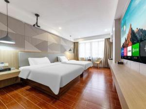 a hotel room with two beds and a flat screen tv at Borrman Hotel Shaoguan Century East Street Fengcai Building in Shaoguan