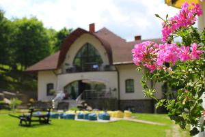 una casa con un patio con flores rosas delante de ella en Villa Kvitka, en Svalyava