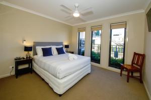 a bedroom with a bed and a chair and windows at 39C Cypress in Mulwala +23 photos