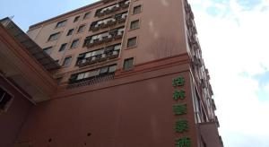 a tall building with green signs on the side of it at Green Tree Inn Guangxi Wuzhou 2nd Xinxing Road Liangguang Market in Wuzhou