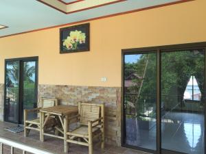 a patio with two chairs and a table and windows at Rainbow Bungalow Haadrin Koh Phangan in Haad Rin