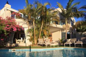 a house with palm trees and a swimming pool at Ocean Watch Guest House in Plettenberg Bay +10 photos