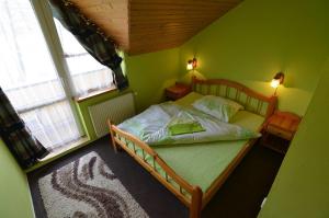 a bedroom with a bed with green walls and two windows at Penzión Prameň in Vinné