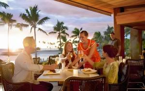 eine Gruppe von Menschen sitzt mit Weingläsern an einem Tisch in der Unterkunft Aulani, A Disney Resort And Spa in Kapolei