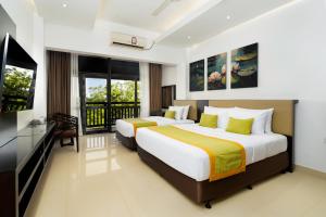 two beds in a hotel room with a television and a balcony at Kynrock Hotels & Resorts Kataragama in Kataragama