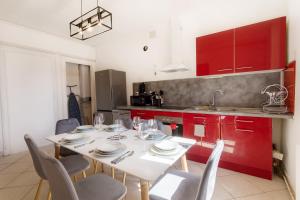 a kitchen with a white table with chairs and red cabinets at Appartement tout équipé au cœur de Beziers 6 à 8 couchages in Béziers