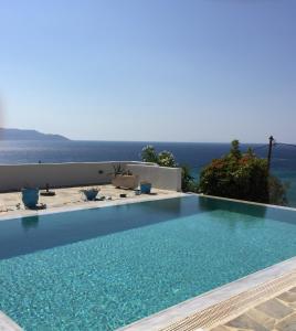 a swimming pool with the ocean in the background at The Grand Beach House in Karistos