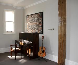 a room with a piano and a guitar on a wall at Verandahs Parkside Lodge in Auckland