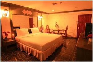 バンコクにある13 コインズ タワー ホテル ラチャダの大きなベッドとテーブルが備わるホテルルームです。