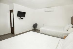 una camera da letto con due letti e una TV a parete di Hotel Jardin De Las Marias a Suchitoto Altre 22 foto