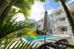 a house with a pool and an umbrella and palm trees at Residence Capri - Mont Choisy in Mont Choisy
