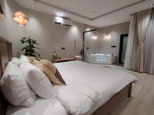 ein Schlafzimmer mit einem großen Bett mit weißen Kissen in der Unterkunft شاليه جريين اوايسس بمسبح وغرفة نوم واحده وصاله وجلسه خارجيه in Al Muţayrifī + 14 Fotos