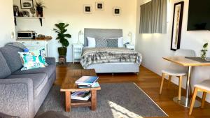a living room with a bed and a couch at Callemondah Studio with stunning views, in Bangalow and Byron Hinterland in Bangalow