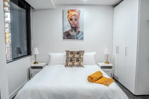 a bedroom with a white bed with a painting on the wall at City Living, Prime Location with Parking & Amenities in Melbourne +37 photos