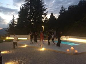 un grupo de personas de pie alrededor de una piscina por la noche en Hotel Nido dell'Aquila en Assergi