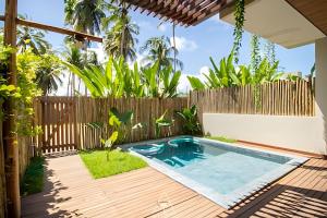 einen Hinterhof mit einem Pool und einem Holzzaun in der Unterkunft Casa Karoá, a Beira-Mar na Rota dos Milagres, Praia de Marceneiro in Barra do Camaragibe